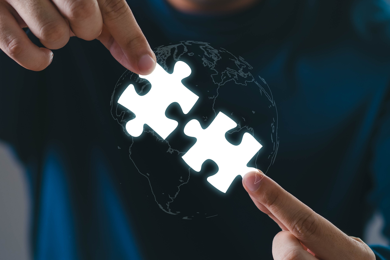 Puzzleteile werden von zwei Händen zusammengeschoben.