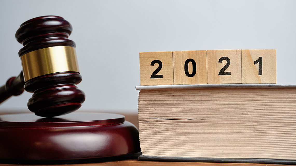Richterhammer liegt neben Gesetztext auf dem Holzwürfel die Jahreszahl 2021 bilden