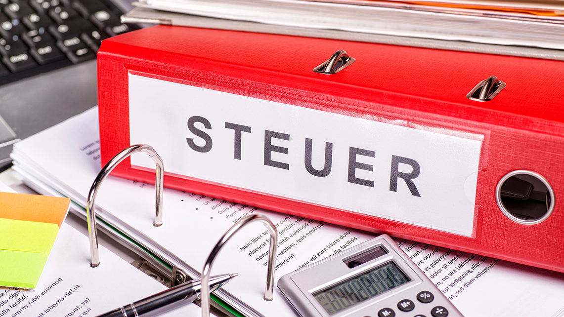 Roter Ordner mit der Beschriftung Steuer liegt auf Unterlagen