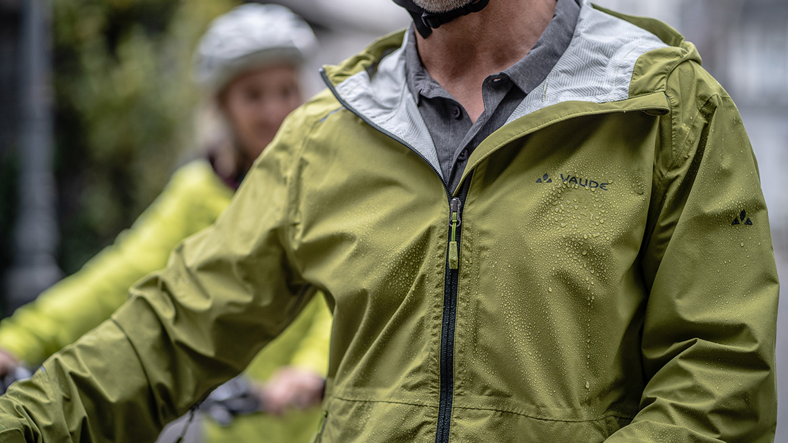 Grüne Regenjacke der Marke Vaude mit Regentropfen