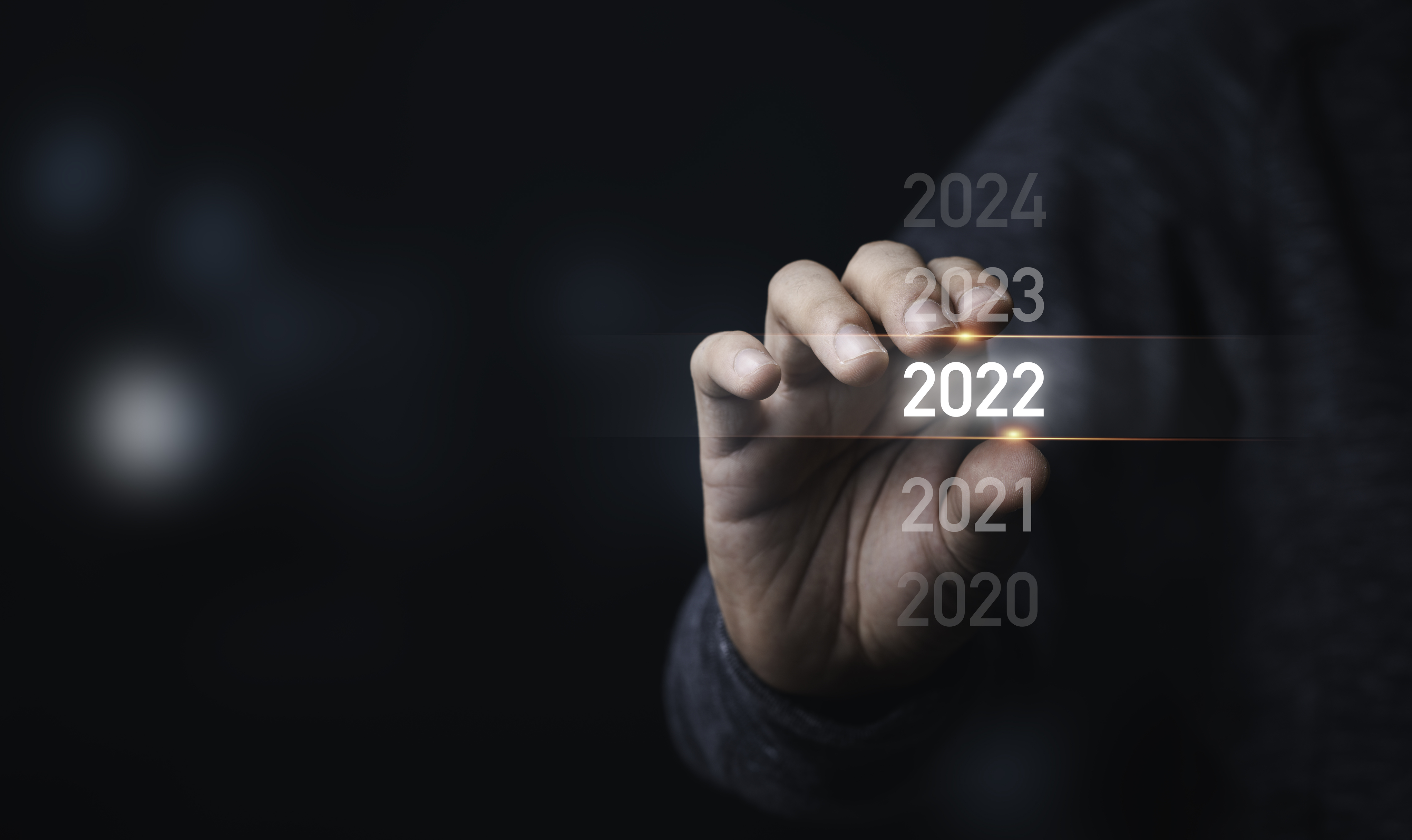 Eine Hand verschiebt einen Lichtbalken von 2022 auf 2023. 
