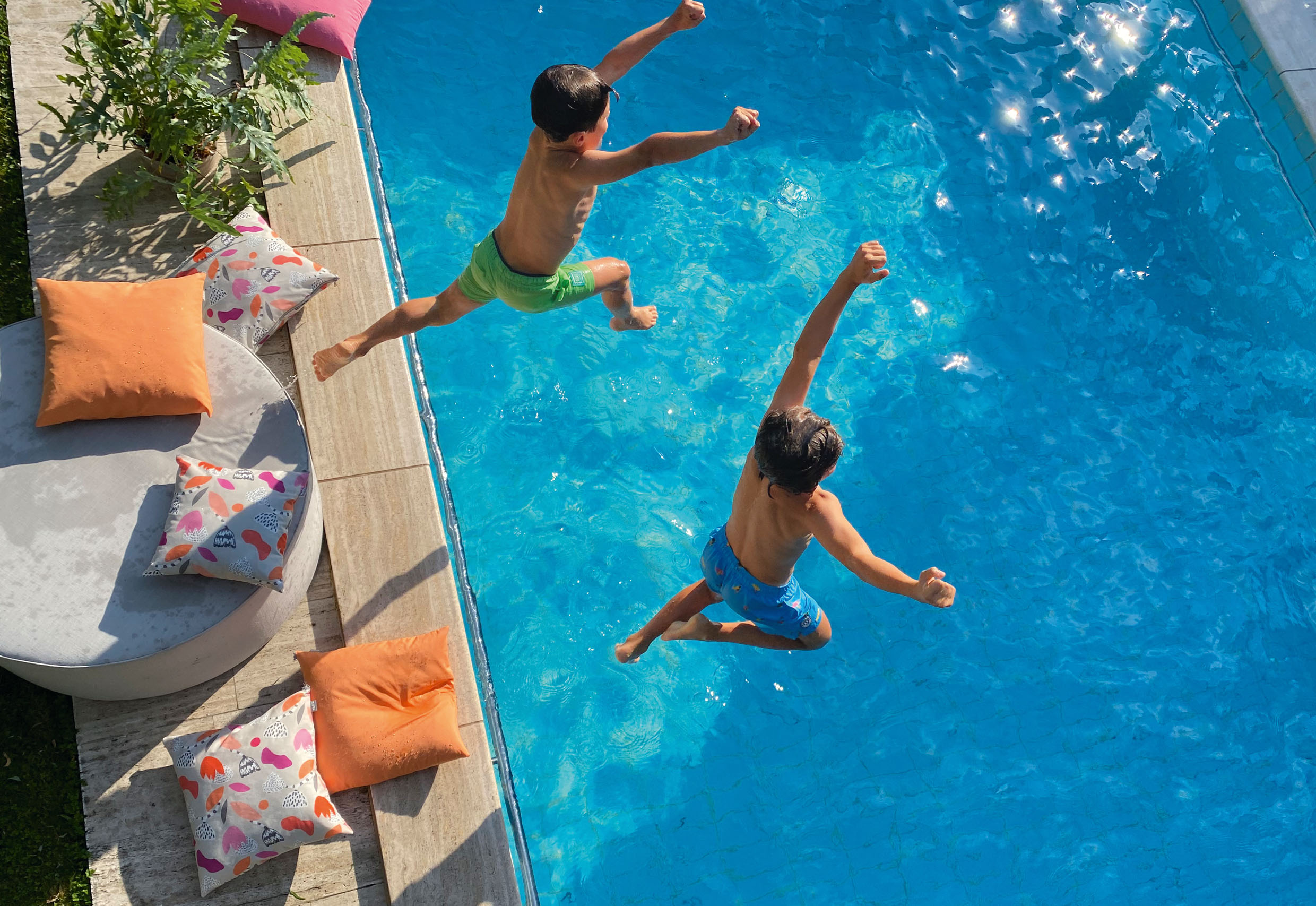 Zwei Kinder springen in einen Pool