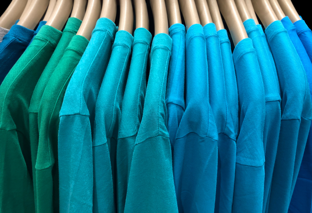 Grüne und blaue T-Shirts auf einem Ständer