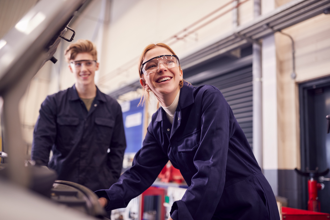 Weibliche und männliche Person, die während der Ausbildung am Fahrzeug arbeiten