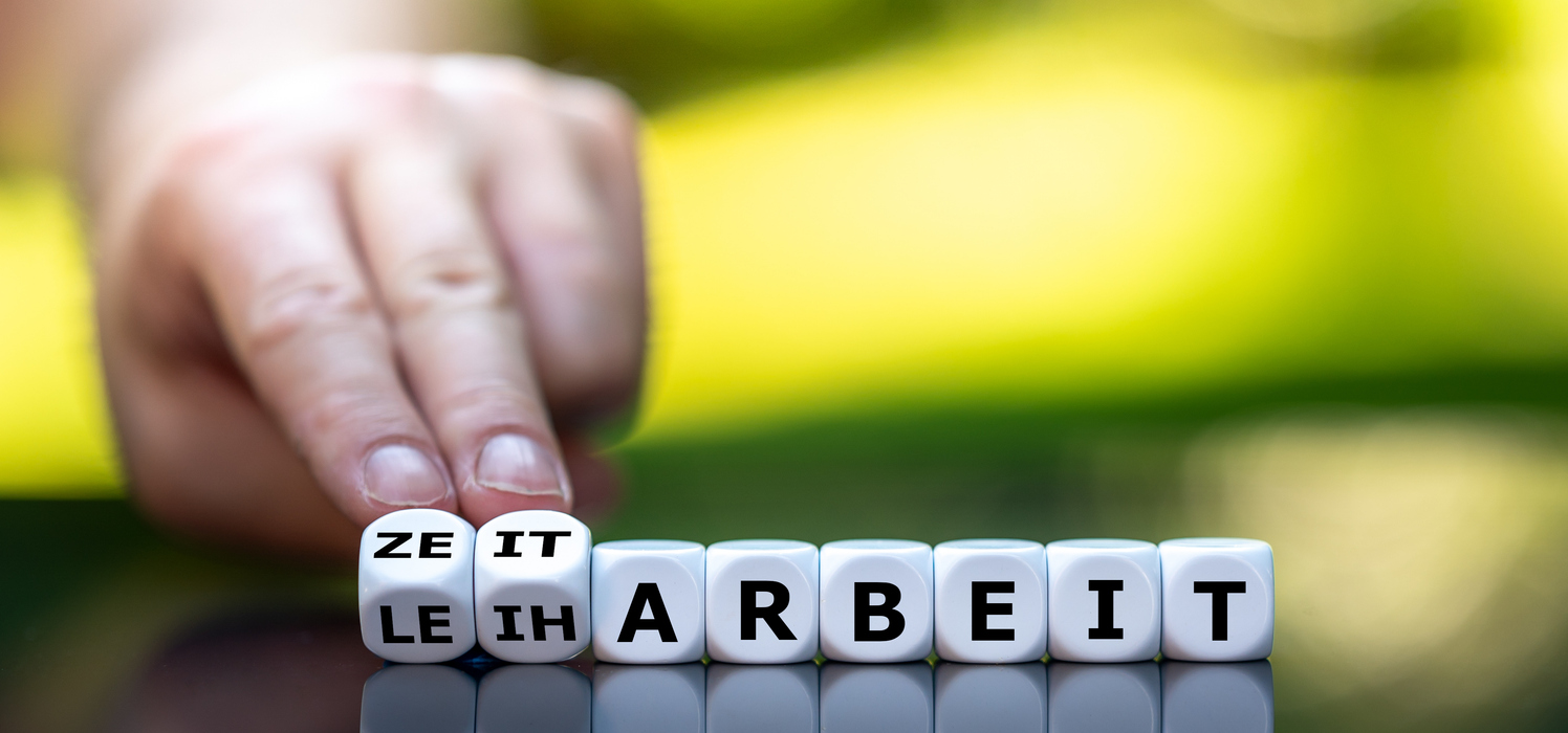 Hand würfelt und ändert das deutsche Wort "Leiharbeit" in "Zeitarbeit".