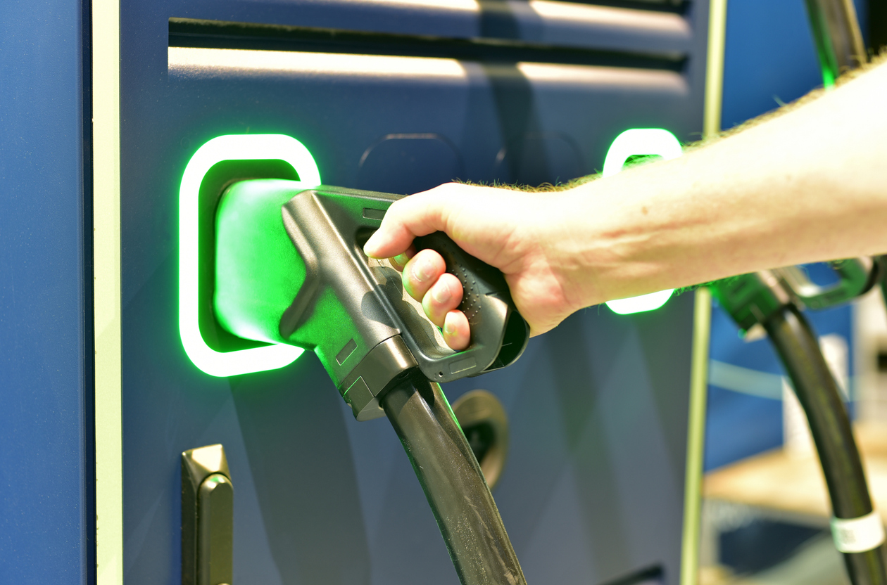 Hand einer Person an einer Ladesäule für E-Fahrzeuge