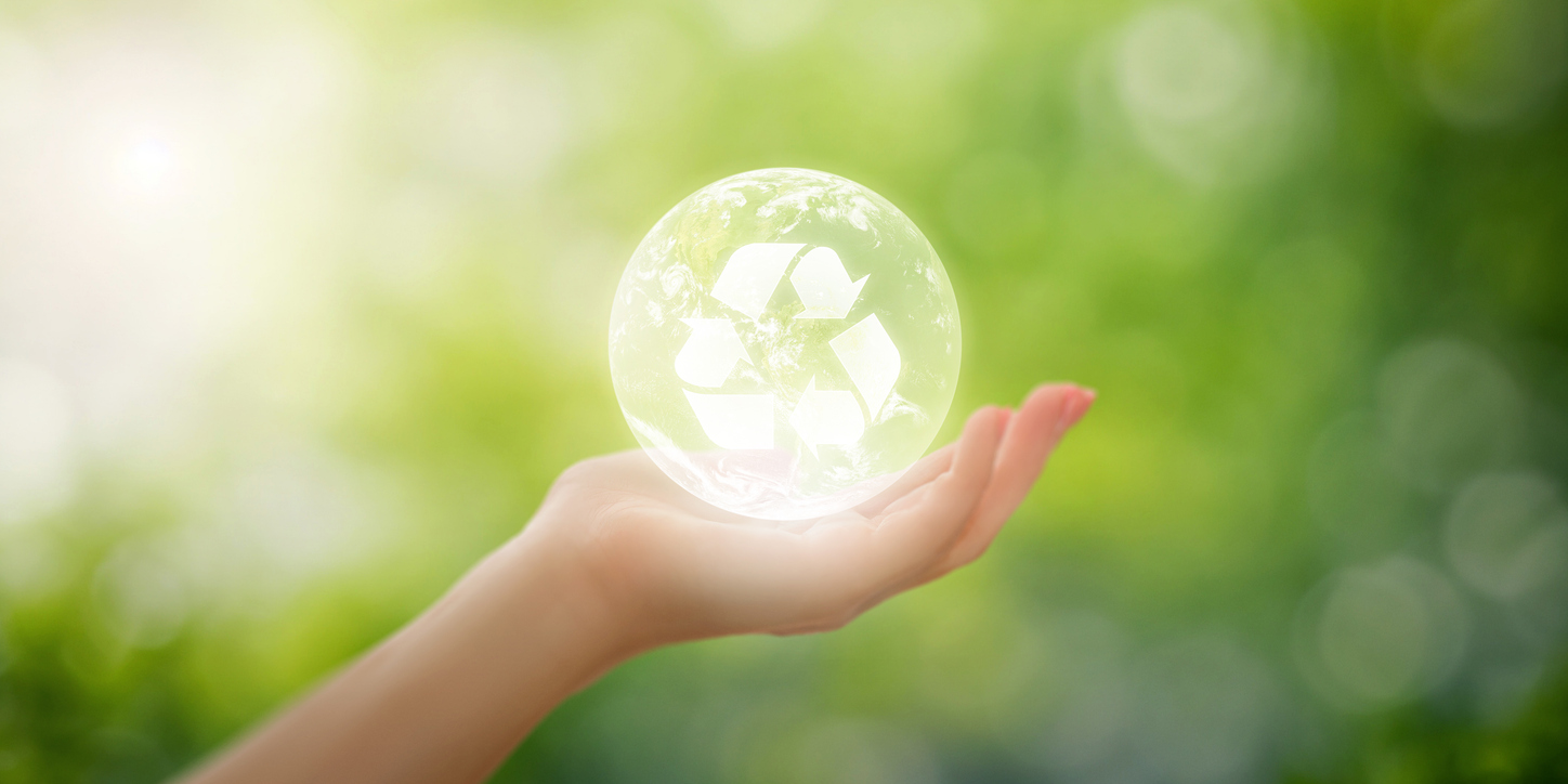 Hand, die Erde mit Recycling-Logo im Inneren auf verschwommenem natürlichem Hintergrund hält