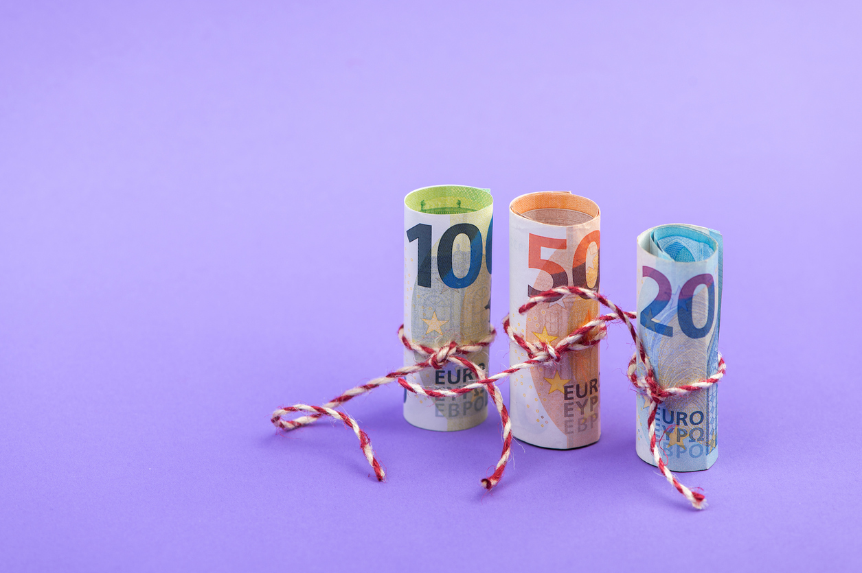 Rollen mit 100-, 50- und 20-Euro-Geldscheinen, isoliert auf hellviolettem Hintergrund