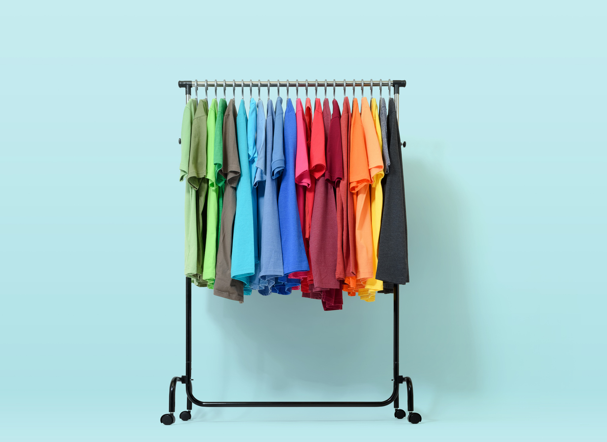 Mobiles Rack mit Farbkleidung auf hellblauem Hintergrund