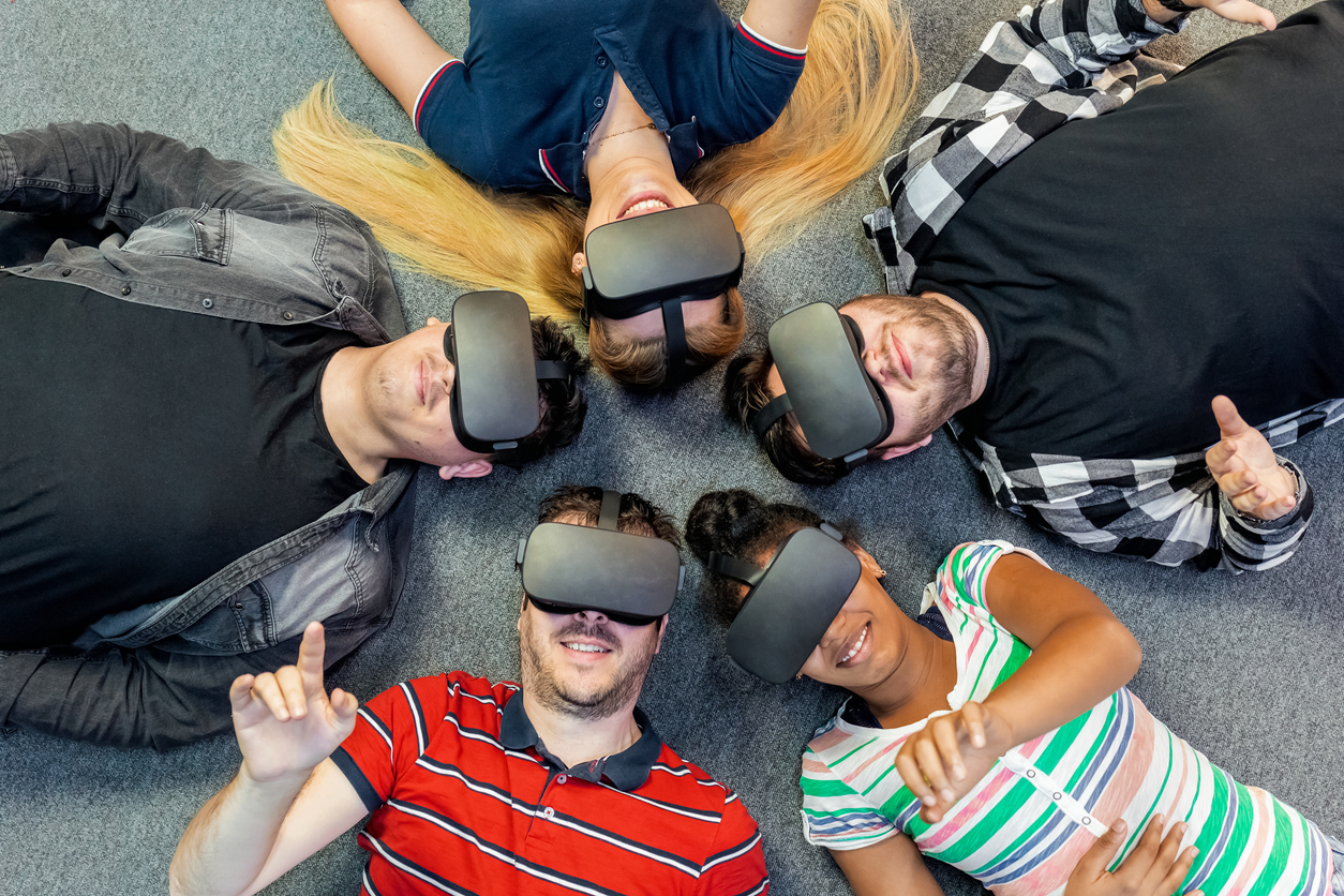 Jugendliche die VR-Brillen tragen liegen beieinander